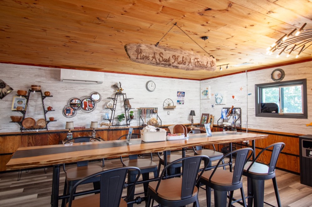 The dining room at The Lakehouse Kitchen, with a long live-edge table and a sign that reads Have a Seat, Make a Friend