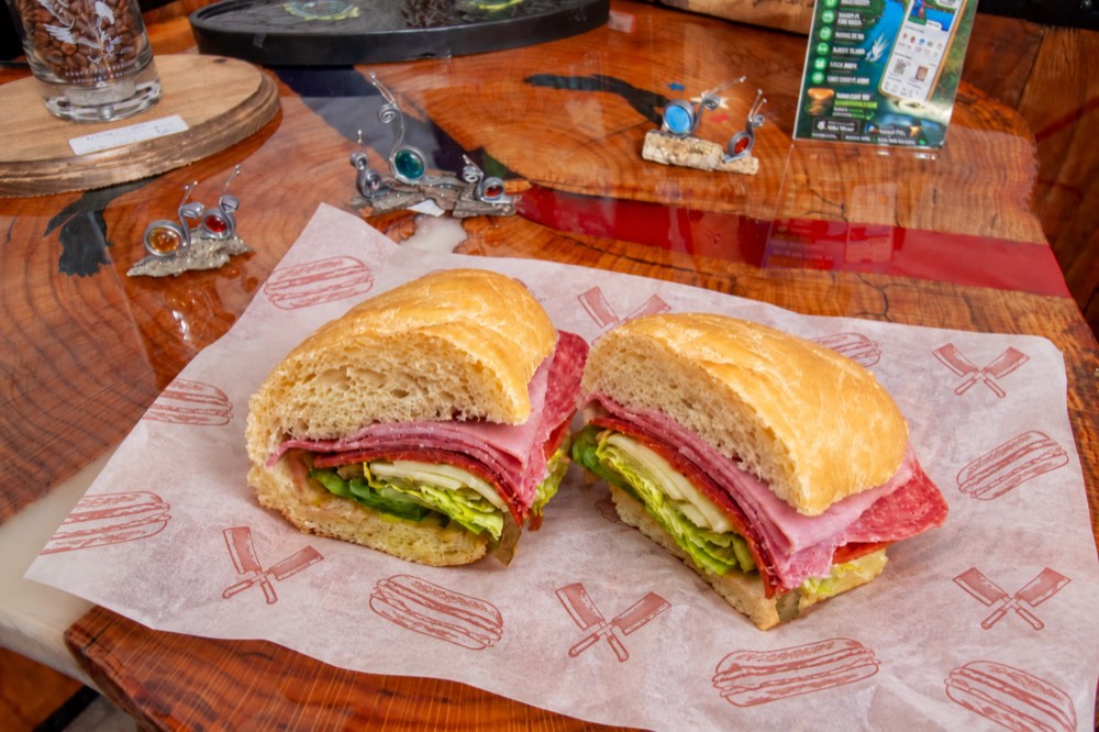 An Italian sub on fresh-baked bread, sliced in half on deli paper